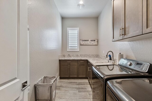 washroom with cabinet space, independent washer and dryer, wood tiled floors, and a textured wall