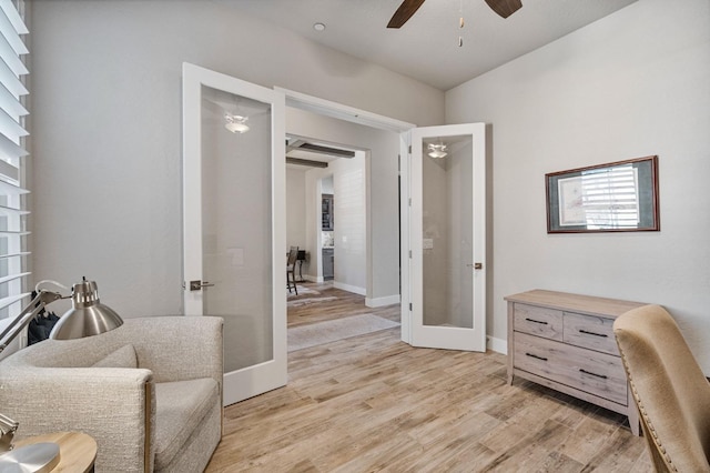 sitting room with french doors, a ceiling fan, light wood finished floors, and baseboards