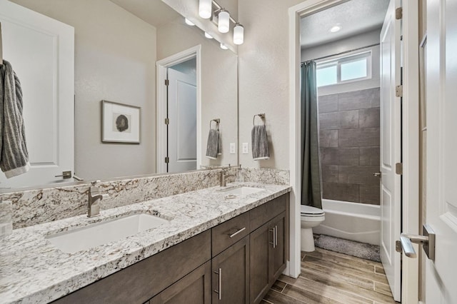 full bathroom featuring toilet, wood finished floors, double vanity, and shower / bathtub combination with curtain