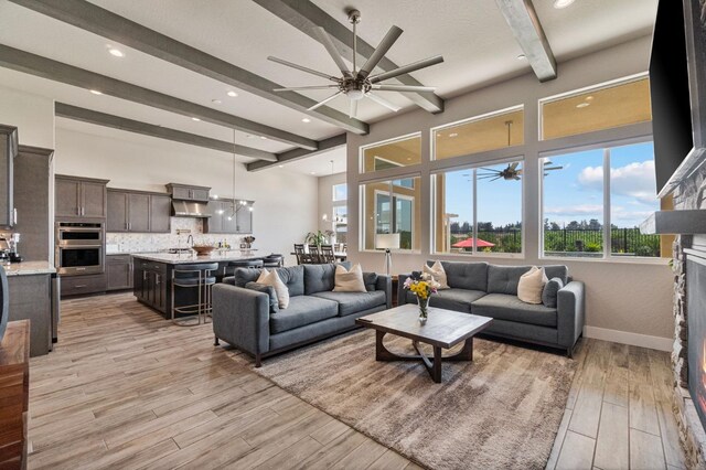 living area with ceiling fan, beam ceiling, light wood-style floors, recessed lighting, and a fireplace
