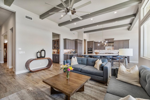 living area featuring light wood-style floors, beam ceiling, ceiling fan, baseboards, and recessed lighting