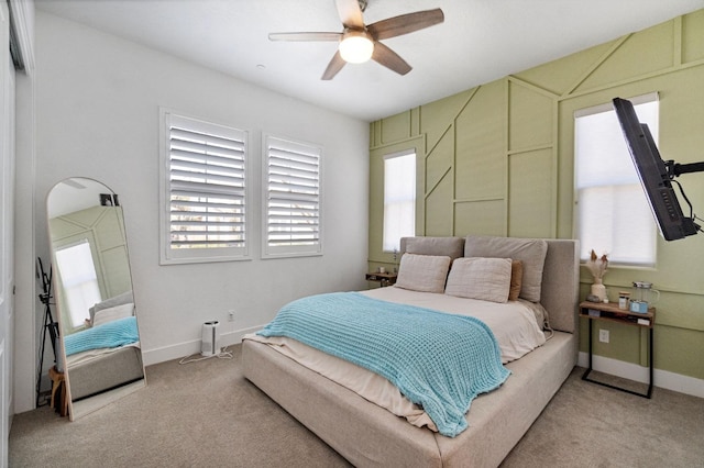 bedroom with light colored carpet, multiple windows, and a ceiling fan