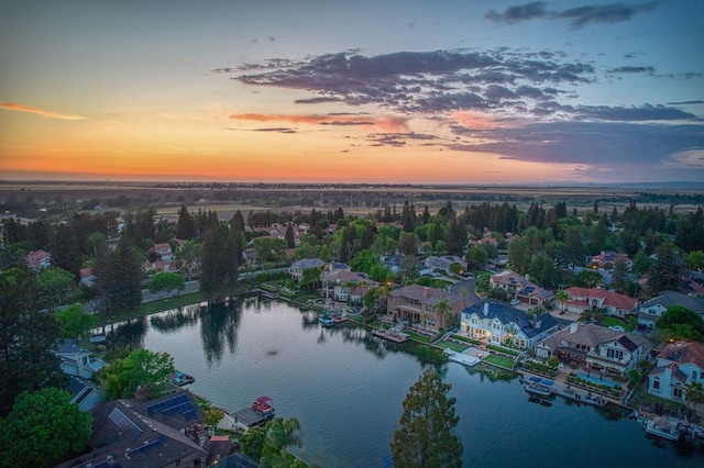aerial view at dusk featuring a water view and a residential view