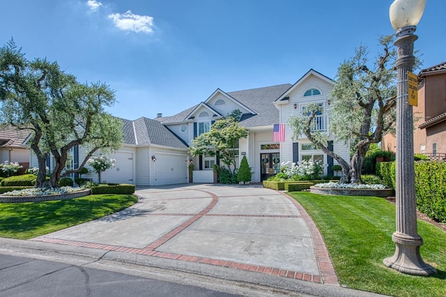 view of front of property with concrete driveway, a front lawn, and a garage