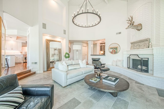 living area with an inviting chandelier, high vaulted ceiling, a brick fireplace, visible vents, and baseboards