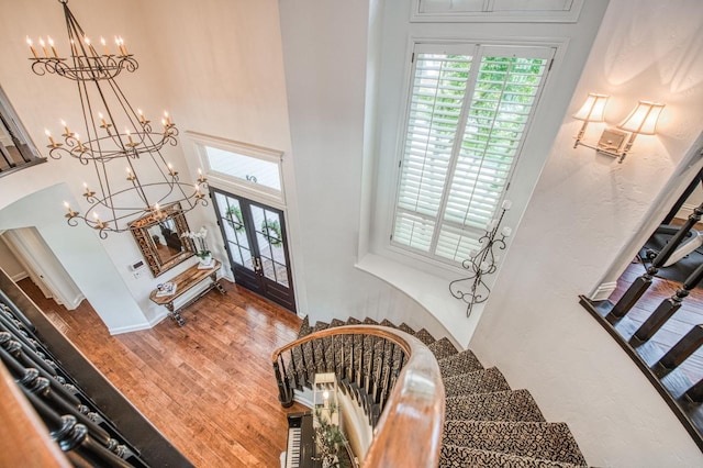 foyer entrance featuring an inviting chandelier, stairway, a towering ceiling, and a healthy amount of sunlight