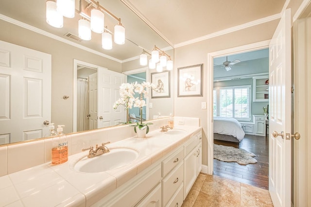 ensuite bathroom featuring a sink, crown molding, and double vanity