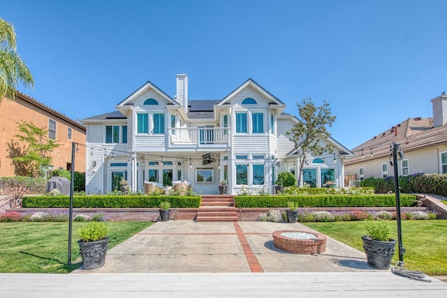 view of front of property featuring a balcony, a front lawn, and solar panels