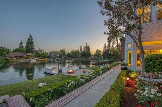 surrounding community featuring a dock, a water view, and a lawn