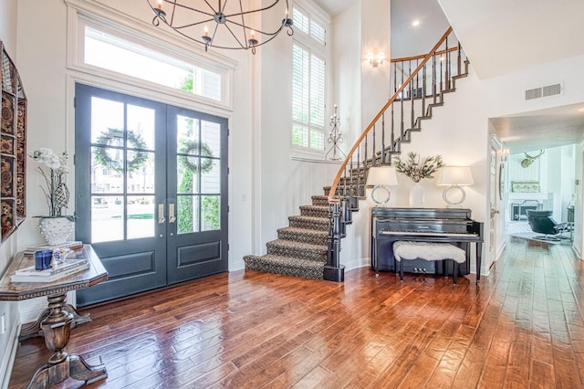 entryway featuring stairs, french doors, visible vents, and a towering ceiling
