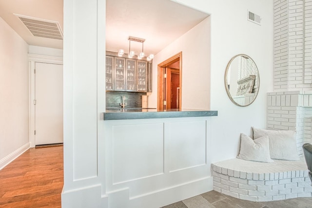 bar featuring decorative light fixtures, baseboards, visible vents, indoor wet bar, and tasteful backsplash