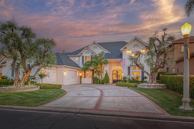 traditional-style house with concrete driveway, a yard, french doors, and an attached garage