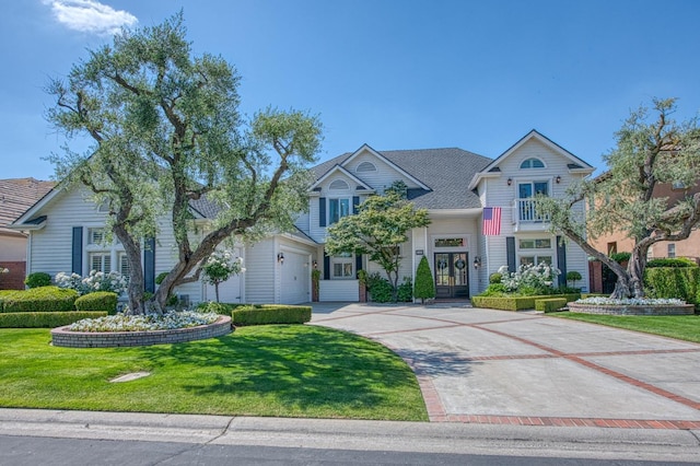 view of front of property featuring a garage, a front lawn, french doors, and driveway