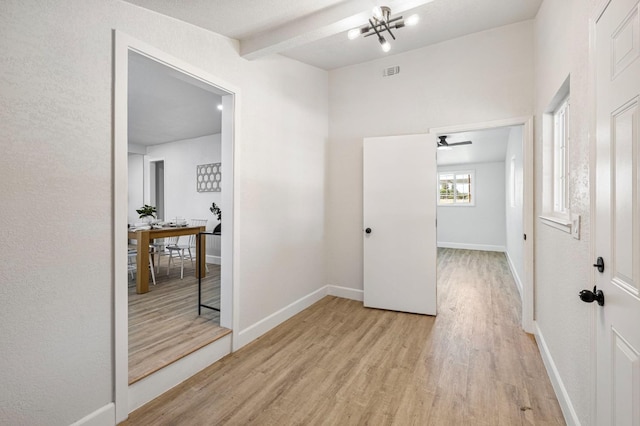 corridor featuring baseboards, beamed ceiling, light wood finished floors, and visible vents