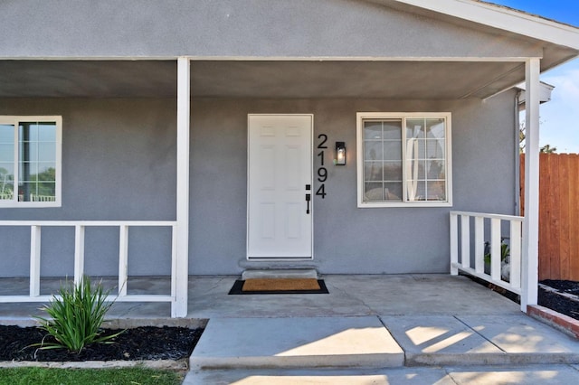 property entrance with stucco siding and a porch