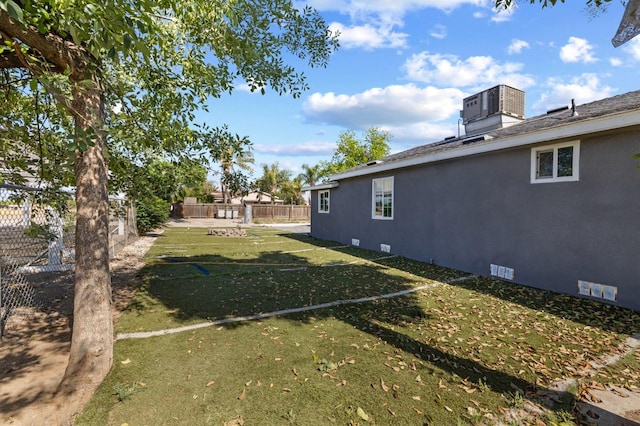 view of yard featuring central AC unit and fence