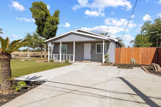 view of front of property with covered porch, stucco siding, fence, concrete driveway, and a front yard