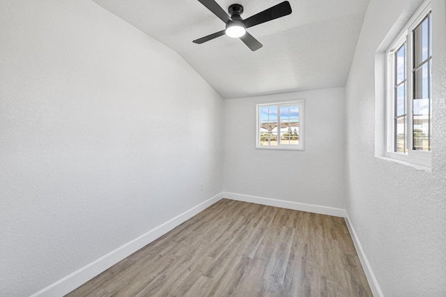 spare room with wood finished floors, vaulted ceiling, baseboards, and ceiling fan