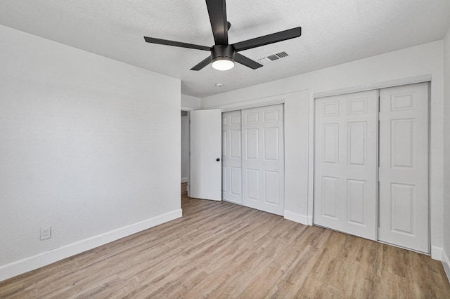 unfurnished bedroom featuring baseboards, visible vents, two closets, and wood finished floors