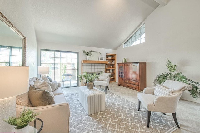 living area featuring light carpet, high vaulted ceiling, and a tile fireplace
