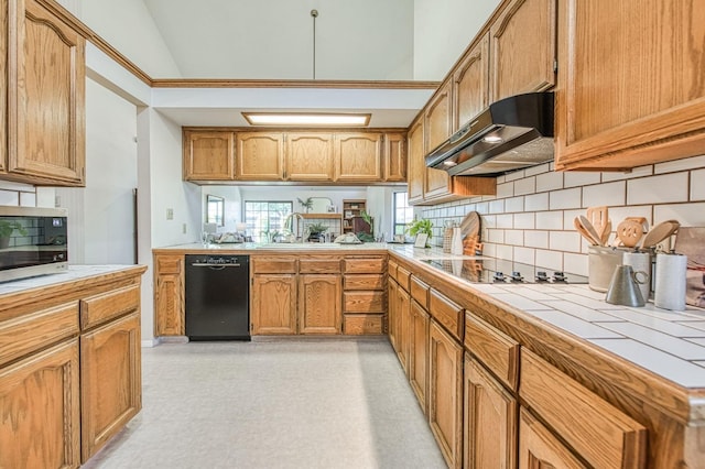 kitchen featuring a sink, tasteful backsplash, black appliances, under cabinet range hood, and tile counters