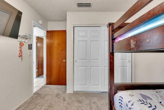 bedroom with light carpet, a textured ceiling, and a closet
