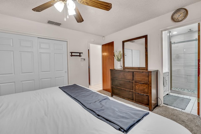bedroom featuring a closet, tile patterned floors, a textured ceiling, ensuite bath, and a ceiling fan