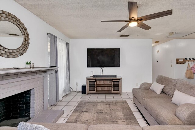 living area featuring tile patterned floors, a textured ceiling, a fireplace, and a ceiling fan