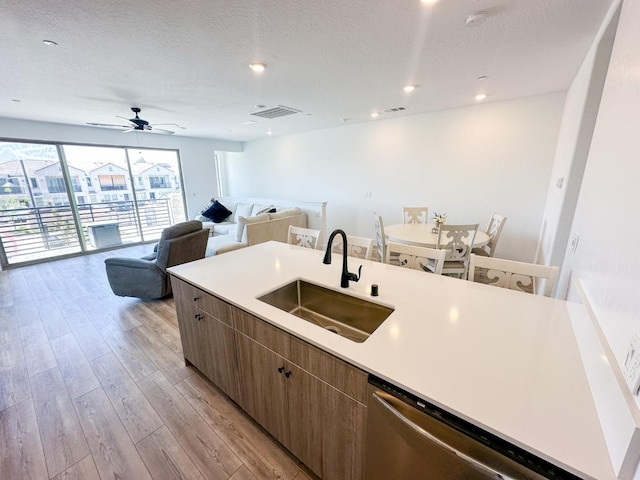 kitchen featuring a sink, stainless steel dishwasher, light wood-style flooring, open floor plan, and a ceiling fan