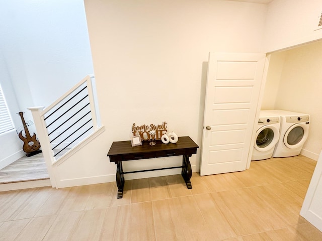 clothes washing area with washer and dryer, baseboards, and light wood-style floors