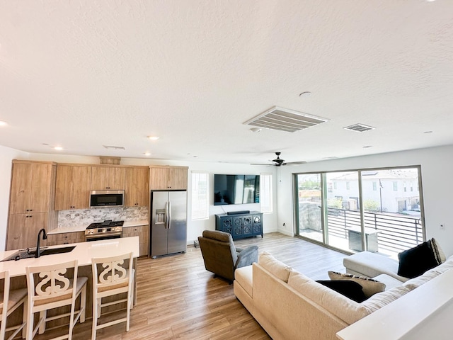 living room with light wood finished floors, ceiling fan, a textured ceiling, and recessed lighting