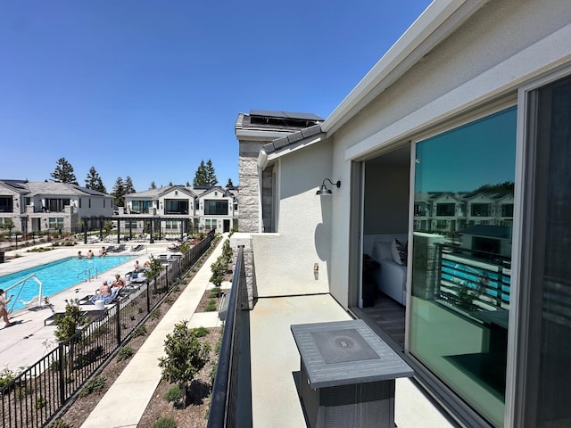 balcony featuring view of pool area and a residential view