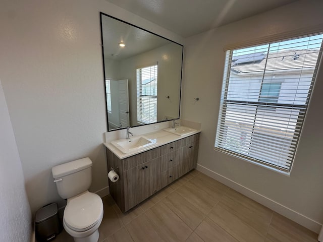 full bath featuring toilet, baseboards, double vanity, and tile patterned flooring