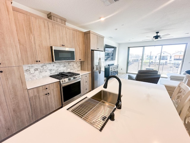 kitchen with stainless steel appliances, light brown cabinets, light countertops, backsplash, and ceiling fan