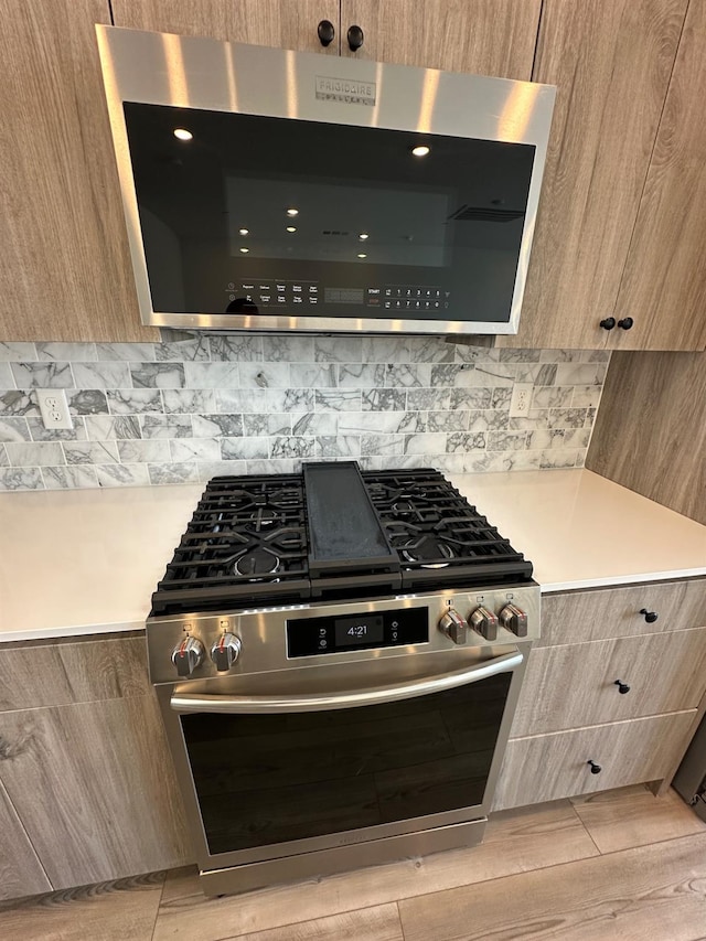 kitchen with gas stove, modern cabinets, light countertops, and tasteful backsplash