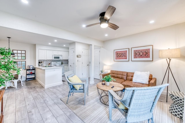living room featuring a ceiling fan, recessed lighting, and light wood finished floors