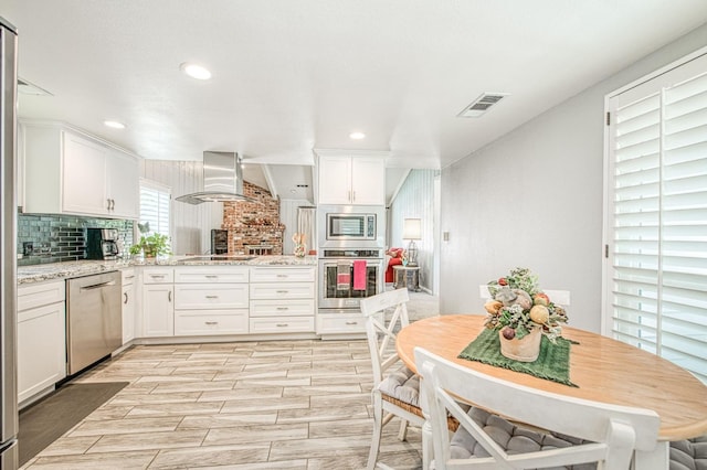 6619 N Valentine Ave, Fresno, CA 93711 - kitchen with appliances with stainless steel finishes, range hood, white cabinetry, tasteful backsplash, and a peninsula