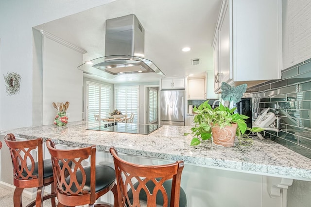6619 N Valentine Ave, Fresno, CA 93711 - kitchen with high quality fridge, island exhaust hood, black electric cooktop, a peninsula, and decorative backsplash