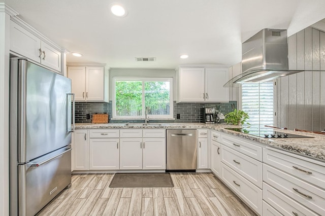 6619 N Valentine Ave, Fresno, CA 93711 - kitchen featuring stainless steel appliances, wall chimney range hood, white cabinets, decorative backsplash, and light wood finished floors