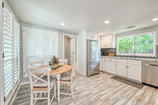 6619 N Valentine Ave, Fresno, CA 93711 - kitchen featuring stainless steel appliances, white cabinets, light stone counters, tasteful backsplash, and light wood-style floors