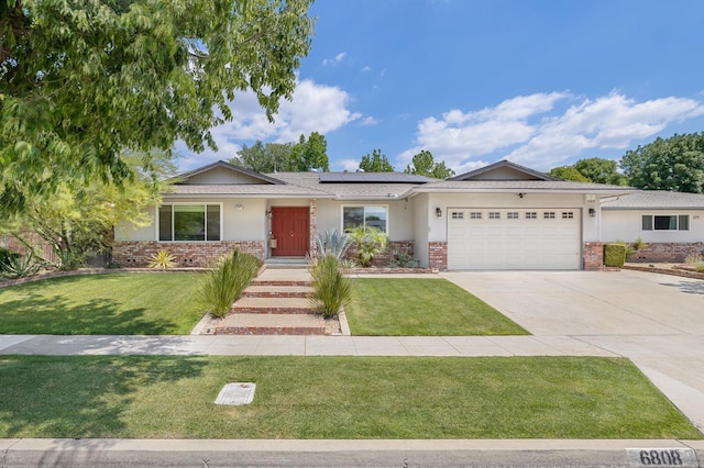 single story home featuring brick siding, a garage, roof mounted solar panels, and a front lawn