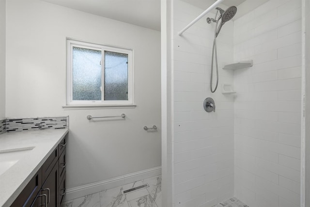 full bath with marble finish floors, tiled shower, vanity, and baseboards