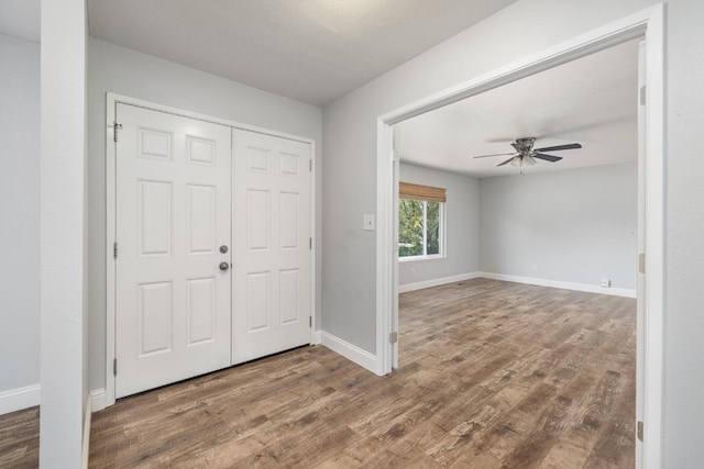 entrance foyer featuring wood finished floors, ceiling fan, and baseboards