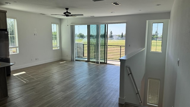 unfurnished living room with dark wood-type flooring, a ceiling fan, and baseboards