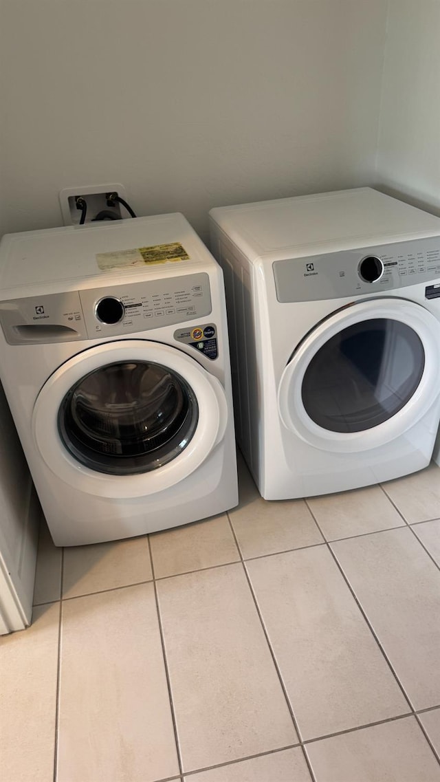 laundry area featuring washer and clothes dryer and light tile patterned flooring