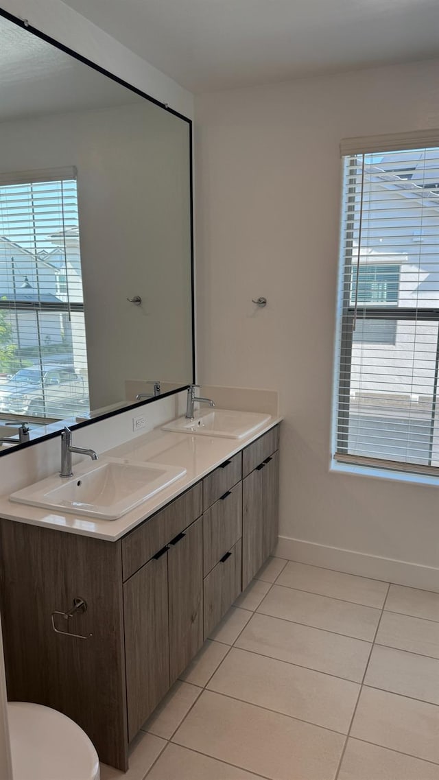 bathroom featuring tile patterned flooring, toilet, double vanity, and baseboards