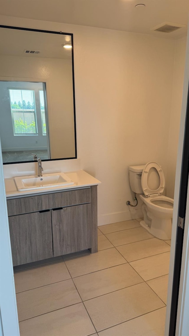 bathroom featuring tile patterned flooring, toilet, baseboards, and vanity