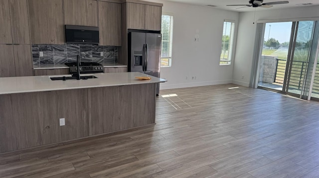 kitchen featuring modern cabinets, light countertops, ceiling fan, a sink, and stainless steel fridge with ice dispenser