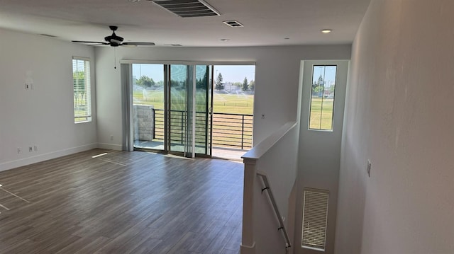 unfurnished room featuring plenty of natural light, dark wood-style floors, baseboards, and a ceiling fan