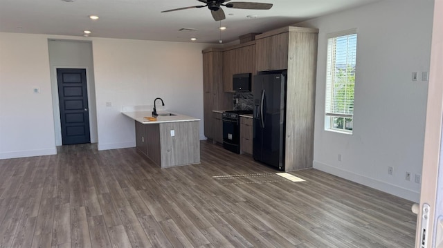 kitchen with black appliances, ceiling fan, light countertops, a sink, and light wood finished floors